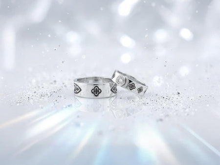 This dark academic ring set captures the mysterious romance of a medieval cathedral. Bright studio lighting highlights the polished silver rims, contrasting dramatically with the pitch-black sulfur oxidation in the carved quatrefoil recesses. Rich in gothic symbolism, the continuous quatrefoil motif represents the intersection of earth and heaven, mirroring the windows of ancient cathedrals. It serves as a profound talisman of eternal devotion an