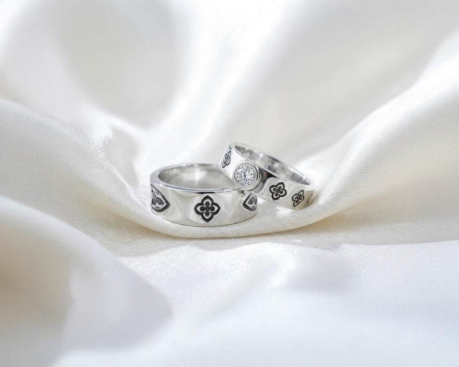 This dark academic ring set captures the mysterious romance of a medieval cathedral. Bright studio lighting highlights the polished silver rims, contrasting dramatically with the pitch-black sulfur oxidation in the carved quatrefoil recesses. Rich in gothic symbolism, the continuous quatrefoil motif represents the intersection of earth and heaven, mirroring the windows of ancient cathedrals. It serves as a profound talisman of eternal devotion an