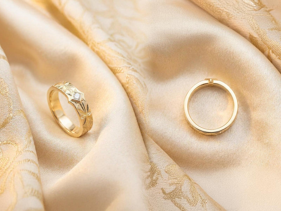 A close-up studio photograph of a matching pair of 925 sterling silver wedding bands resting on a bright, reflective white surface scattered with tiny crystals. The rings feature a continuous, deeply engraved pattern of geometric starbursts or celestial stars with radiating lines. The primary band has a square, princess-cut light blue gemstone, likely blue topaz or aquamarine, bezel-set directly into the center of the prominent front-facing star.