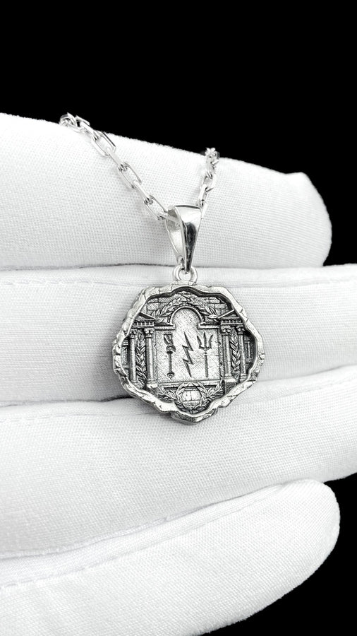 A close-up studio photograph of a 925 sterling silver Greek mythology pendant on a black background. The amulet features a detailed relief of a classical temple housing three figures - Poseidon, Zeus, and Athena. This striking pendant captures the majesty of Mount Olympus. Bright studio lighting illuminates the polished silver gods and temple columns, while pitch-black sulfur oxidation fills the deep crevices between the stone architecture.