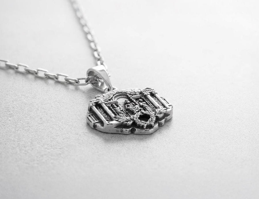 A close-up studio photograph of a 925 sterling silver Greek mythology pendant on a black background. The amulet features a detailed relief of a classical temple housing three figures - Poseidon, Zeus, and Athena. This striking pendant captures the majesty of Mount Olympus. Bright studio lighting illuminates the polished silver gods and temple columns, while pitch-black sulfur oxidation fills the deep crevices between the stone architecture.
