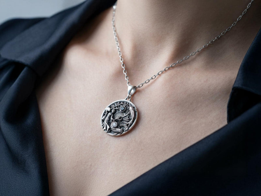Crafted from solid 925 sterling silver, this intricate medallion demonstrates the visual impact of an antiqued patina. The heavy oxidation settles into the carved pagoda and the detailed scales of the koi fish. A dark black onyx and a sparkling clear gemstone add striking contrast to the silver.