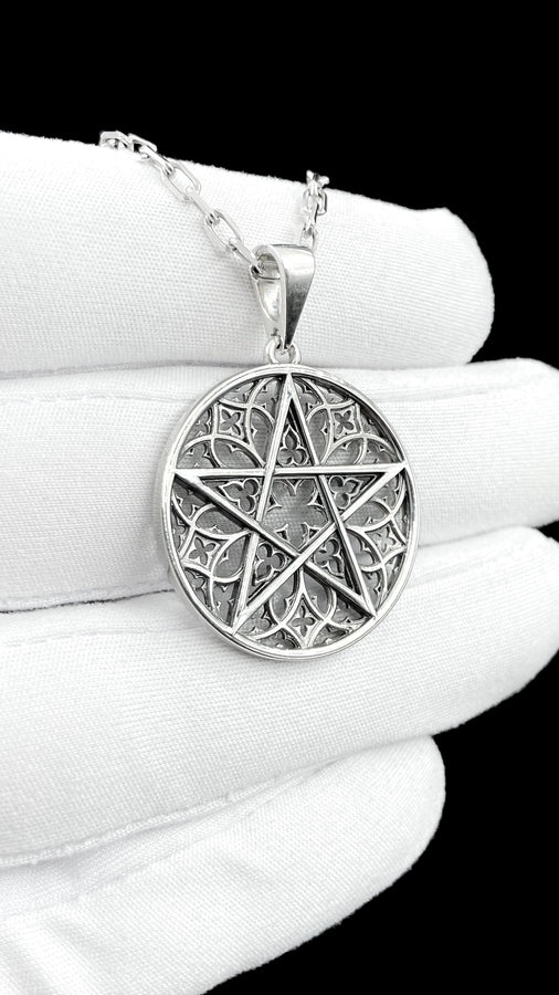 A close-up studio photograph of image_61ba46.png, a circular 925 sterling silver pendant on a black background. The design features a bold, sharp pentagram overlapping an intricate background of openwork gothic cathedral tracery and carved quatrefoil motifs. This striking artisan pendant captures the mesmerizing geometry of medieval architecture. Bright studio lighting illuminates the highly polished lines of the silver five-pointed star, contras