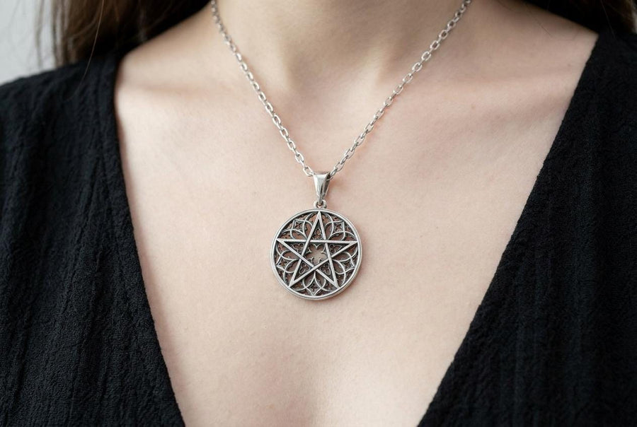A close-up studio photograph of image_61ba46.png, a circular 925 sterling silver pendant on a black background. The design features a bold, sharp pentagram overlapping an intricate background of openwork gothic cathedral tracery and carved quatrefoil motifs. This striking artisan pendant captures the mesmerizing geometry of medieval architecture. Bright studio lighting illuminates the highly polished lines of the silver five-pointed star, contras