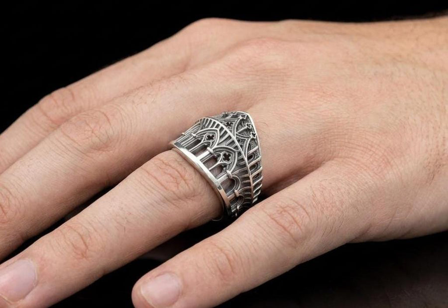 This striking artisan ring perfectly captures the monumental scale of medieval architecture. Bright studio lighting illuminates the polished silver arches and columns, contrasting beautifully with the deep, dark oxidation inside the hollow windows and recesses. Crafted from premium solid 925 sterling silver, this wide architectural band demonstrates the visual impact of an antiqued patina. Heavy sulfur oxidation settles into the intricate crevice