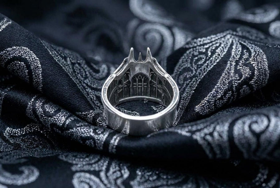 This solid 925 sterling silver gothic cathedral ring features soaring spires and intricately carved pointed arches. Resting on a grey surface, this oxidized silver band showcases detailed medieval tracery and classic stonework columns, perfect for a dark romance aesthetic. A striking 925 sterling silver architecture ring capturing the monumental scale of medieval sanctuaries. Bright lighting illuminates the polished silver gothic spires, contrast