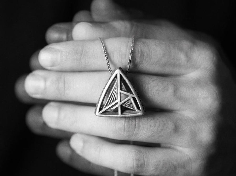 Embrace the structural elegance of modern ruins and sacred geometry. This architectural silver triangle pendant is a bold statement piece, designed for those who find beauty in precise lines and open space. Crafted from 925 sterling silver, the necklace features a complex, three-dimensional geometric framework that creates a captivating optical depth, making it a true centerpiece of alternative jewelry. The avant-garde triangular design features
