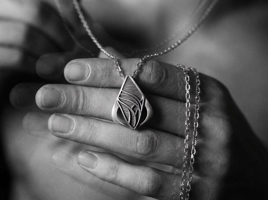Embrace the fluid elegance of dark fantasy and organic architecture. This sweeping silver teardrop pendant is a striking statement piece, designed for those who are captivated by the seamless blend of natural forms and futuristic biomechanics. Crafted from solid 925 sterling silver, this amulet offers a sophisticated touch of avant-garde mystique to any alternative look. A close-up studio photograph of a 925 sterling silver sci-fi pendant resting