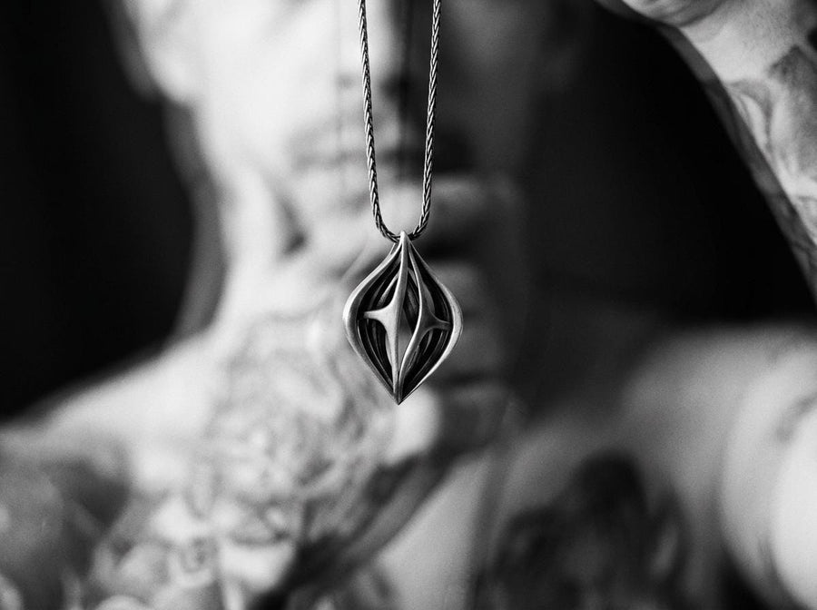 Atmospheric shot of a solid sterling silver alien artifact necklace, featuring sweeping organic geometric arches.