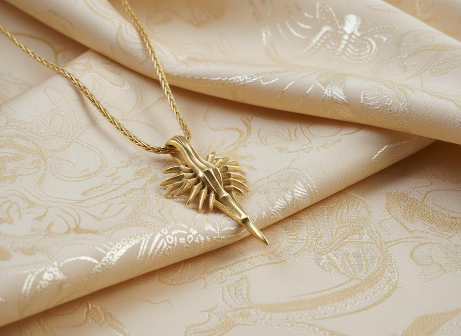 Close-up of a man's hand holding a solid sterling silver alien weapon necklace, showing the sharp elongated drop.