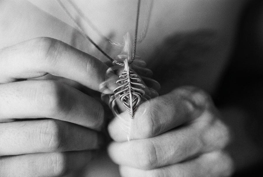 Avant-garde dark fantasy jewelry piece: a striking 3D skeletal silver drop charm hanging from an anchor chain.