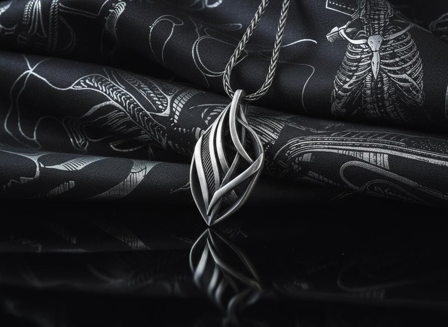 Dark fantasy silver teardrop pendant resting on black fabric, showing sweeping organic lines and an oxidized micro-ribbed background.