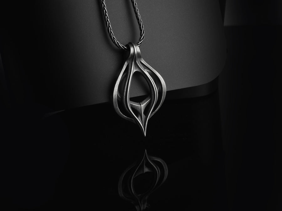 Oxidized biomechanical teardrop pendant suspended on an anchor chain, emphasizing its airy cut-out structure.