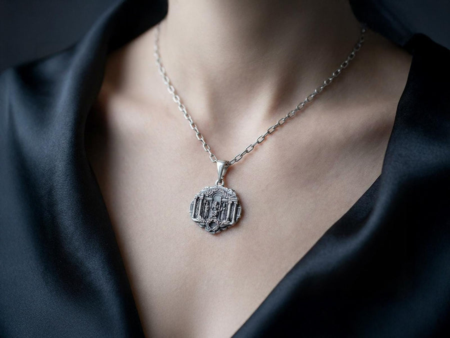 A close-up studio photograph of a 925 sterling silver Greek mythology pendant on a black background. The amulet features a detailed relief of a classical temple housing three figures - Poseidon, Zeus, and Athena. This striking pendant captures the majesty of Mount Olympus. Bright studio lighting illuminates the polished silver gods and temple columns, while pitch-black sulfur oxidation fills the deep crevices between the stone architecture.