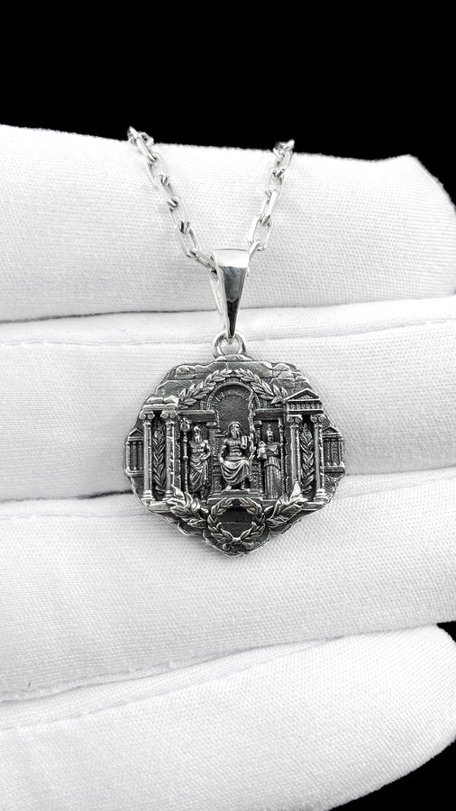 A close-up studio photograph of a 925 sterling silver Greek mythology pendant on a black background. The amulet features a detailed relief of a classical temple housing three figures - Poseidon, Zeus, and Athena. This striking pendant captures the majesty of Mount Olympus. Bright studio lighting illuminates the polished silver gods and temple columns, while pitch-black sulfur oxidation fills the deep crevices between the stone architecture.