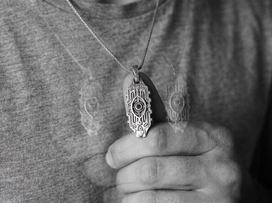 Intricate cyberpunk design inspired by high-tech circuitry and sci-fi artifacts. Exceptional silversmithing is evident in this oxidized silver avant-garde necklace. The relief work perfectly balances the sharp lines of the outer mechanical border with the central red gemstone core. A bold cyberpunk statement piece for alternative collectors.