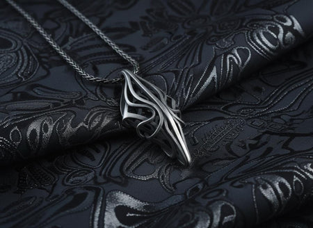 Handcrafted with care, safely packaged, and ready for worldwide shipping. A close-up studio photograph of a 925 sterling silver geometric pendant resting on a light grey surface. The avant-garde design features elongated, sweeping silver curves forming an abstract openwork diamond shape, highlighted by a dark oxidized finish. This striking artisan pendant from ArtFoxJewelryStudio captures the essence of fluid modern sculpture.