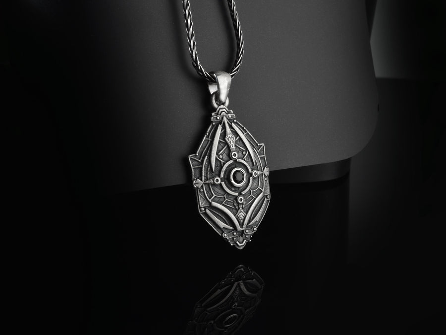 Unique artisan crafted silver armor necklace for men, fantasy sci-fi jewelry, A close-up studio photograph of a 925 sterling silver shield pendant resting on a dark reflective surface. The avant-garde design features geometric plating and a central circular core, highlighted by a dark matte oxidized finish. This striking artisan pendant captures the essence of futuristic armor.