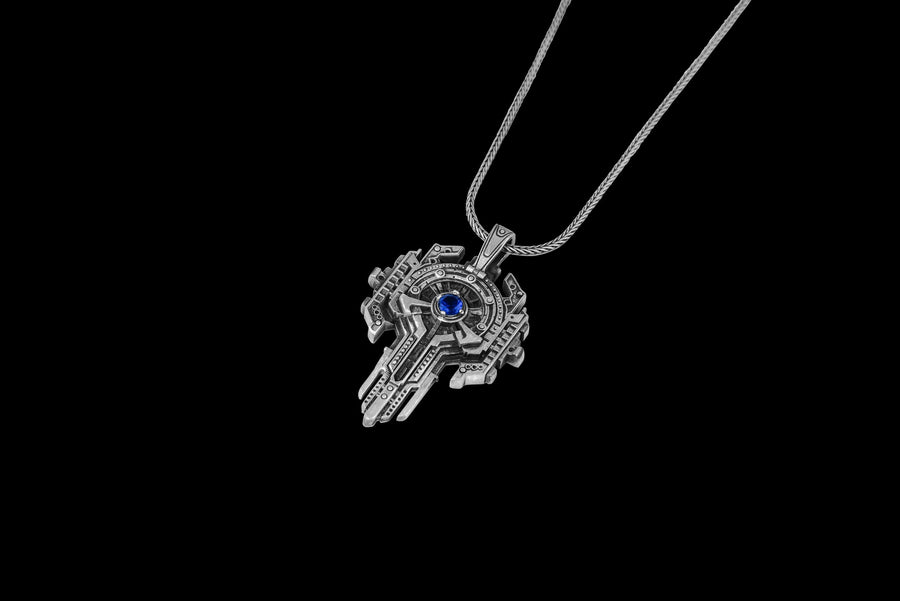 Front view of an oxidized silver sci-fi key necklace with a central blue stone isolated on white.