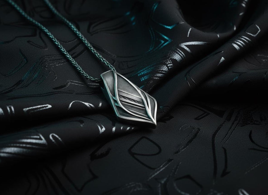 The pendant features a striking elongated shield silhouette, heavily detailed with precise micro-engraved lines and stippled textures that echo industrial elements. These darkened, oxidized recesses contrast brilliantly against the sharply polished, sweeping outer ridges. The multi-layered, armor-like plates give the piece incredible optical depth and a tactile, industrial feel.