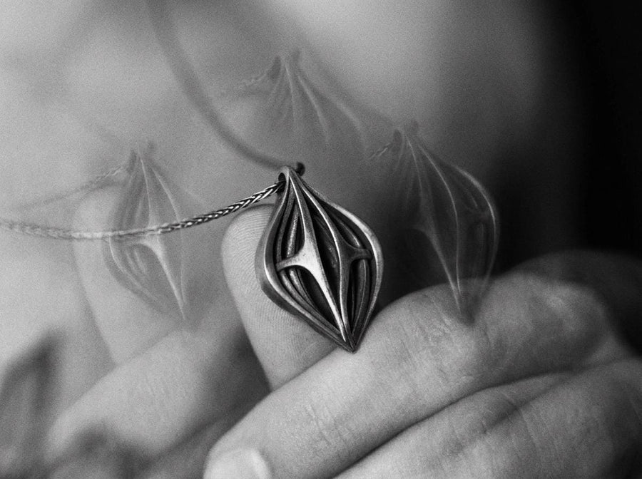 Atmospheric shot of a solid sterling silver alien artifact necklace, featuring sweeping organic geometric arches.