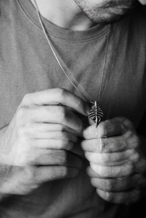 Avant-garde dark fantasy jewelry piece: a striking 3D skeletal silver drop charm hanging from an anchor chain.