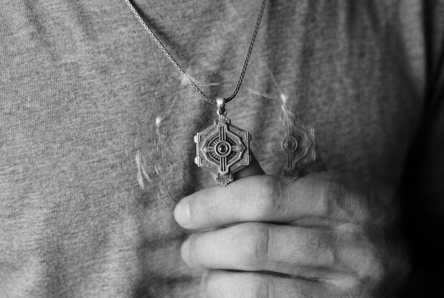 Cyberpunk silver hexagon pendant resting on a bare chest, showing a mechanical design centered around a blue stone.