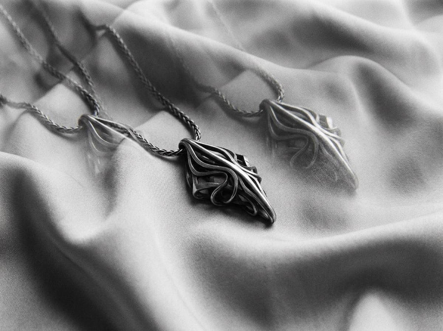 Choose between an Anchor or Foxtail chain to complete your look. Heavy oxidation settles into the textured inner curves, giving this openwork geometric pendant a shadowed, minimalist character.Exceptional silversmithing is evident in this oxidized silver avant-garde necklace. The relief work perfectly balances the sharp structural points with smooth, sweeping interlaced inner curves. A bold modern statement piece for alternative jewelry collector