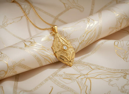 24K Gold coated fantasy shield pendant with a clear center gemstone on silk fabric.