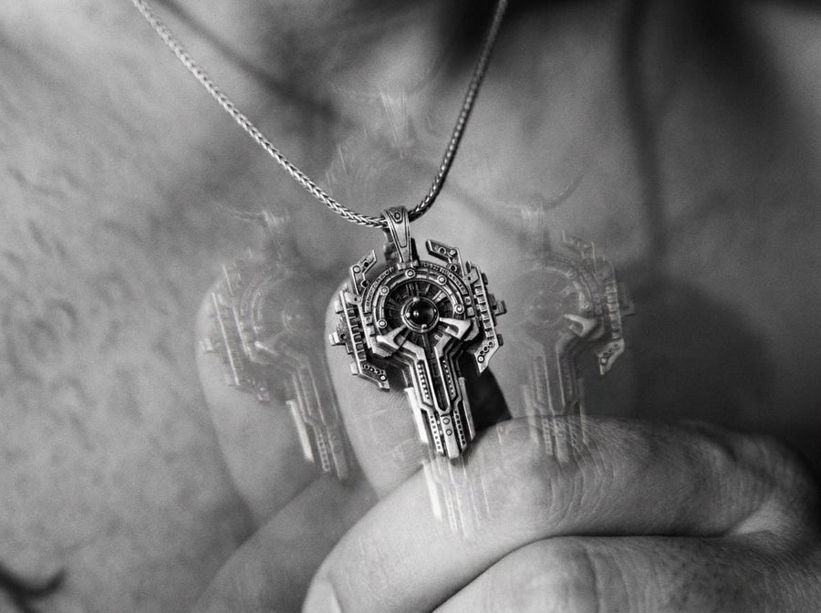 Front view of an oxidized silver sci-fi key necklace with a central blue stone isolated on white.